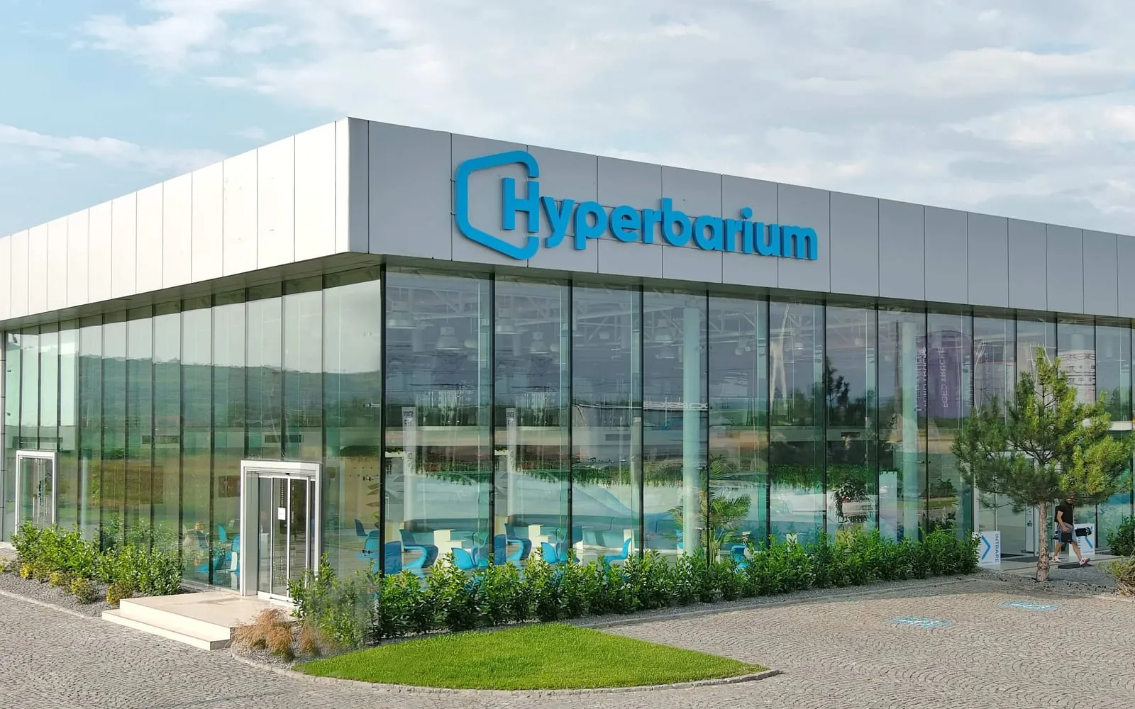 The operational Hyperbarium clinic — a two-storey glass pavilion seen from the forecourt